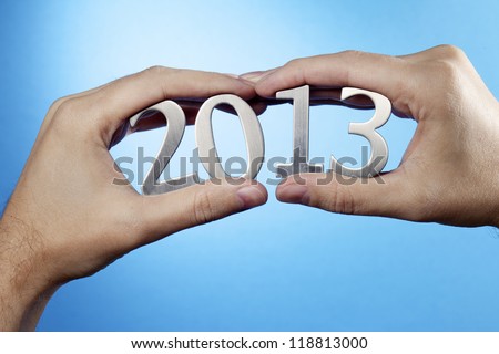 Happy New Year 2013. Man holding metallic numbers 2013 in his hands.