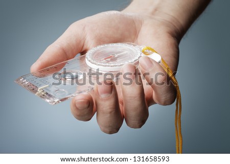 Man holding a liquid-filled protractor or orienteering compass in his hand.