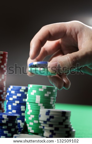 Man lifting two gambling chips from stacks with his hand.