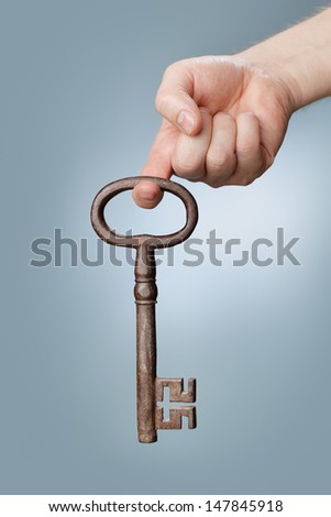 A Large old antique skeleton key hanging from a finger.