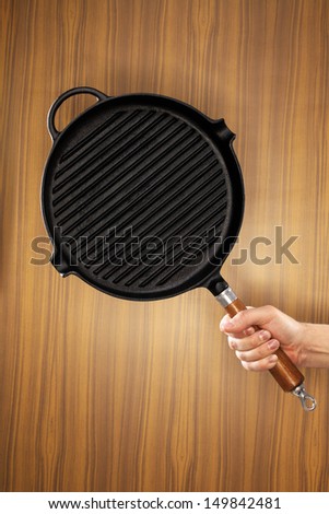Man holding a cast iron frying pan of grill pan type.