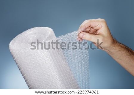 Man holding a roll of plastic bubble wrap.