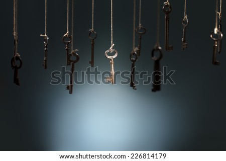 Old keys hanging on strings. One key in the middle is in spotlight focus.