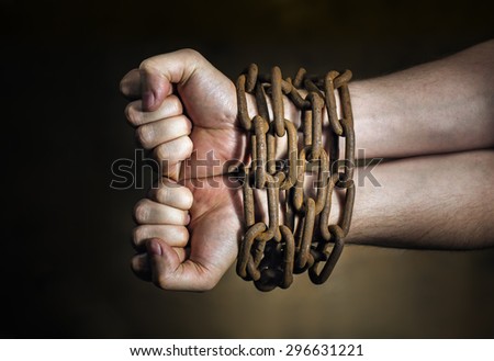 Hands of a man with a rusty chain around the wrists.