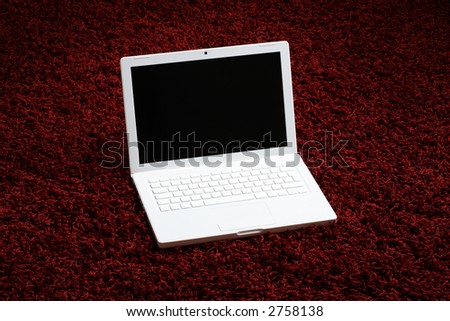 White laptop computer on a red rug