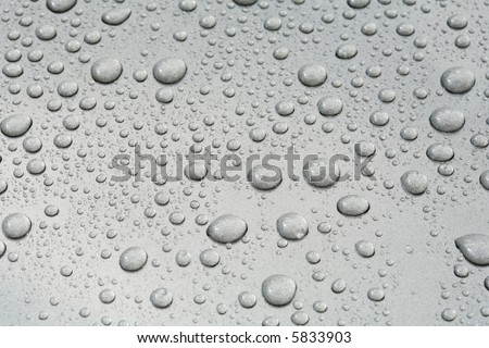 Water beads on a metallic grey car