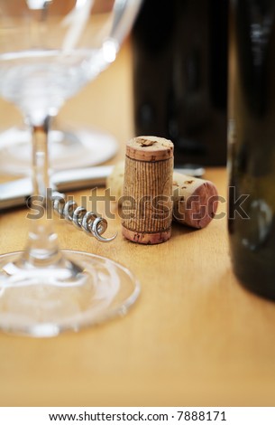 Used wine bottle corks and a cork screw on a table. Short depth-of-field.