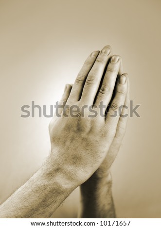 Sepia toned photograph of hand clasped in prayer