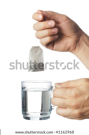 Hand putting a tea bag into a transparent glass cup of hot water