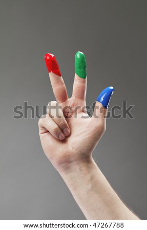 Fingers with fingerpaints in three primary colors, Red, green and blue.