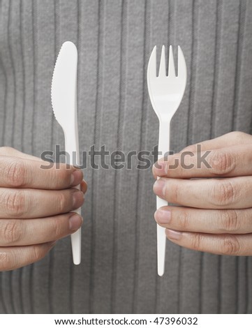 Man holding white disposable cutlery. Knife and fork.
