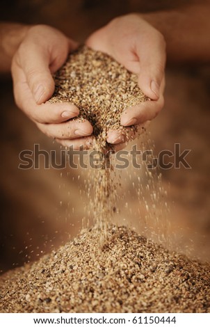 Man adding coarse sand to a heap with his hands. Very shallow depth-of-field and motion blur.