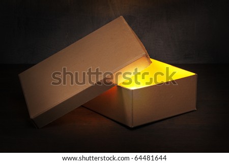 An Old brown cardboard box with glowing contents.