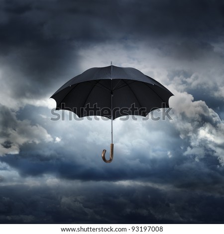 Old black umbrella against rainy sky.