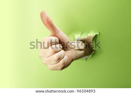 Man making thumb up gesture trough green paper.
