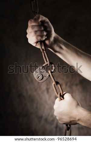 Man holding an old rusty chain and lock in his hands.