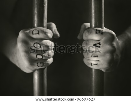 stock photo Man with fake Good and Evil tattoos behind prison bars