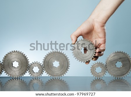 Man adding a cog gear in a row of old cog gears.