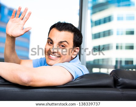 Young Man Looking Behind From Couch And Waving Hello