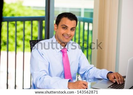 Portrait of a busy guy taking notes, browsing the web on his laptop, and smiling, isolated on city and nature background