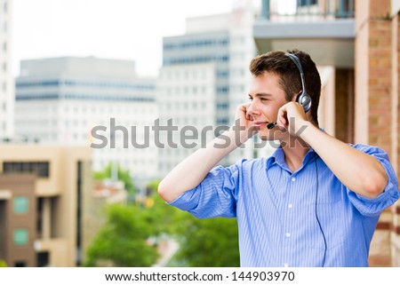Closeup portrait of customer service representative or call center agent or support or operator with headset on outside balcony, isolated on outside background with trees