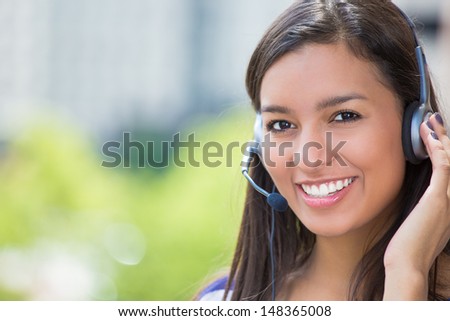 Closeup portrait of customer service representative or call center agent or support staff or operator with headset on outside balcony, isolated on outside background with trees and city buildings