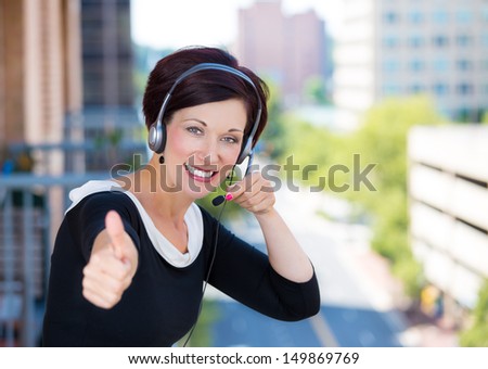 Closeup portrait of customer service representative, call center agent, support staff or operator with headset on outside balcony, isolated on a background with trees and city buildings.Apartment rent