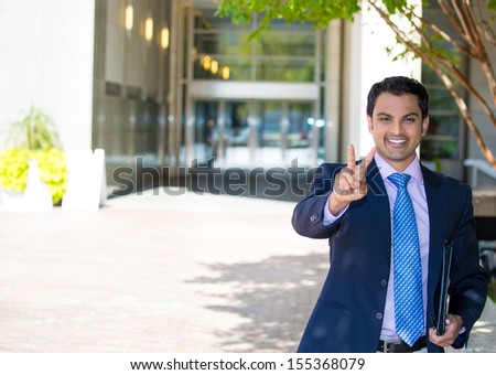 Closeup portrait of handsome young, happy, smiling, successful businessman in suit giving a victory sign on a sunny day, isolated on a city urban background. Corporate, executive life, career