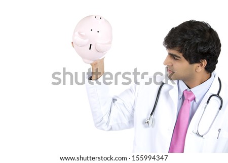 Closeup portrait of a health care professional or doctor or nurse holding piggy bank upside down and showing there is no money there, isolated on white background with copy space. Health care reform.