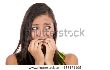 Close-up portrait of a young woman scared ,afraid and anxious biting her finger nails, looking away on to the side, with wide opened eyes isolated on a white background. Human emotions