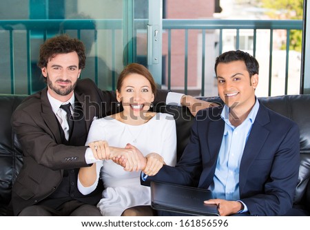 Closeup portrait of woman trying to force a deal and handshake between two men of different races sitting on black couch in apartment, home or office, isolated on a city urban background