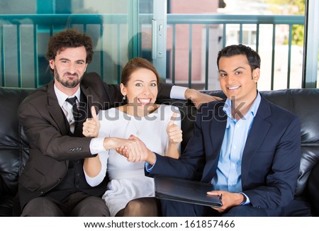 Closeup portrait of woman trying to force a deal and thumbs up sign between two men of different races sitting on black couch in apartment, home or office, isolated on a city urban background