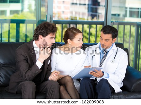 Closeup portrait of serious health care professional or doctor or nurse showing explaining results of test to worried young couple on black couch in office, isolated on city urban background