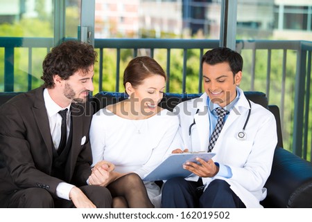 Closeup portrait of smiling health care professional or doctor or nurse showing explaining testing results to happy young successful couple on black couch in office, isolated on city urban background