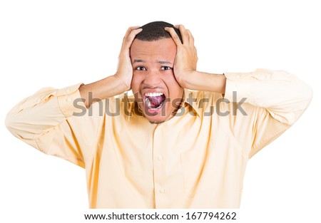 Closeup portrait of a young angry unhappy stressed man covering his ears looking at camera to say, stop making that loud noise it\'s giving me a headache, isolated on white background. Negative emotion