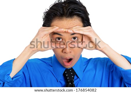 Closeup portrait of young man, looking curious, surprised, shocked through his fingers like binoculars, searching something looking ahead to future, isolated on white background. Human face expression