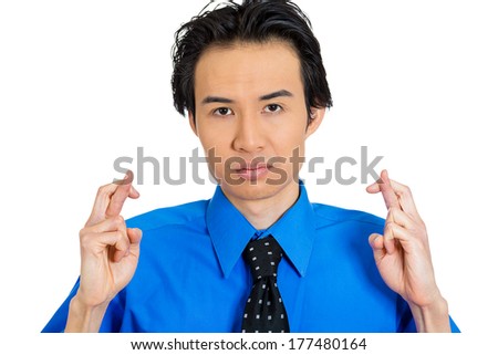 Closeup portrait of young serious man crossing fingers, wishing, praying for miracle, hoping for the best, isolated on white background. Positive human emotions, facial expressions, feelings attitude