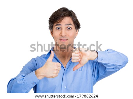 Closeup portrait of confused young man pointing in two different directions, not sure which way to go in life, showing thumbs up, down simultaneously, isolated on white background. Emotion, expression