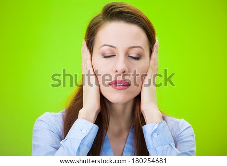 Closeup portrait of attractive, peaceful, looking relaxed young woman, covering ears, closing her eyes, isolated on green background. Hear no evil concept. Human emotions, facial expression, attitude