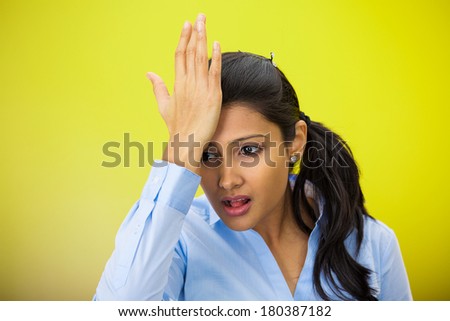 Closeup portrait of confused young woman placing hand on head, palm on face gesture in duh moment, isolated on yellow, green background. Negative emotion facial expression feelings, body language