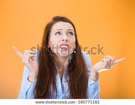 Closeup portrait of confused young woman pointing in two different directions, not sure which way to go in life, isolated on orange background. Negative emotion facial expression feeling body language