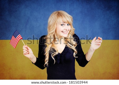 Closeup portrait of beautiful Ukrainian blonde smiling woman holding USA flag in one hand, isolated on Ukraine national flag background. Politics, revolution, Russia conflict protection, negotiation