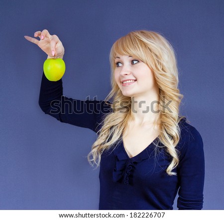 Closeup portrait young happy smiling woman, holding green fresh apple, thinking, looking at it, having idea, solution, isolated dark blue background. Natural organic food concept farming. Expressions