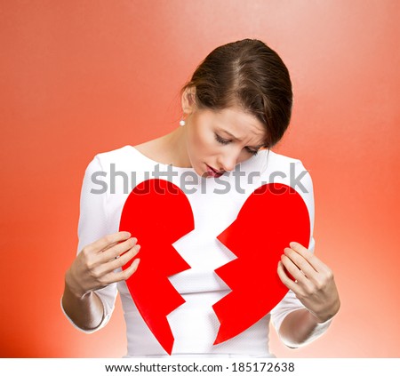 Closeup portrait young, troubled, sad, confused woman, holding broken heart in hands, about to cry, isolated red background. Negative human emotions, facial expression, feelings, attitude, reaction