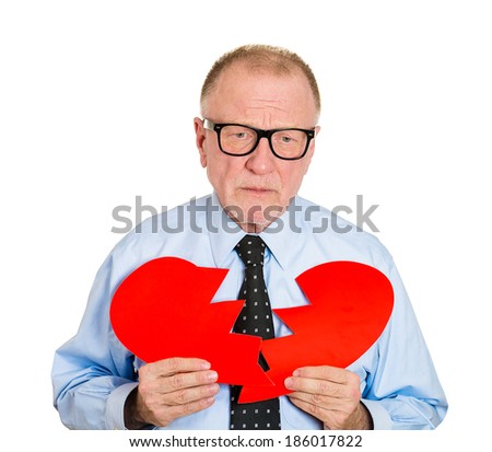 Closeup portrait, senior mature, sad confused man in black glasses, holding broken heart in hands, about to cry, isolated white background. Negative human emotion facial expression feelings, attitude