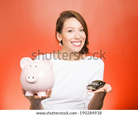 Closeup portrait, beautiful, young woman, dealership agent holding model black car, pink piggy bank in hand, offering credit line, isolated red background. Lease, automobile purchase, financing.