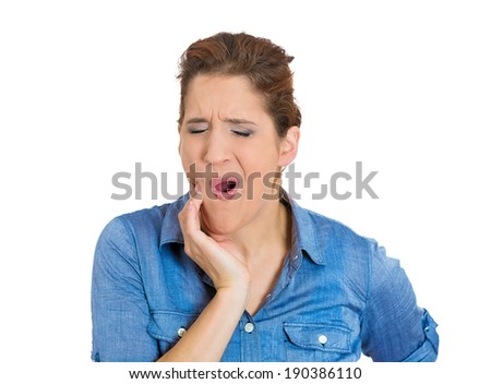 Closeup portrait, young woman with sensitive tooth ache crown problem about to cry from pain touching outside mouth with hand, isolated white background. Negative emotion facial expression feeling