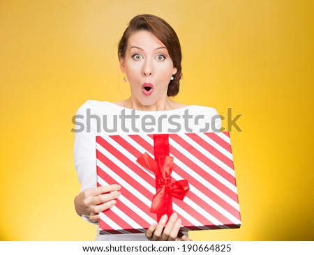 Closeup portrait happy super excited, surprised young woman, received unexpected gift box,opened eyes, mouth isolated yellow background. Positive emotion, facial expression, feeling, attitude reaction