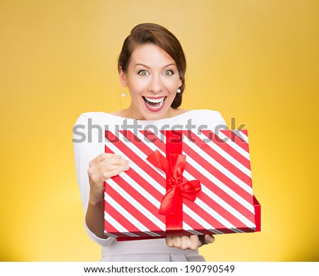 Closeup portrait happy, super excited young woman about to open, unwrap red birthday gift box, isolated yellow background. Positive human emotions, facial expressions, feelings, attitude, reaction