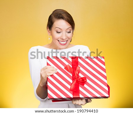 Closeup portrait happy, super excited young woman, lady about to open, unwrap birthday gift box, isolated yellow background. Positive human emotions, facial expressions, feelings, attitude, reaction